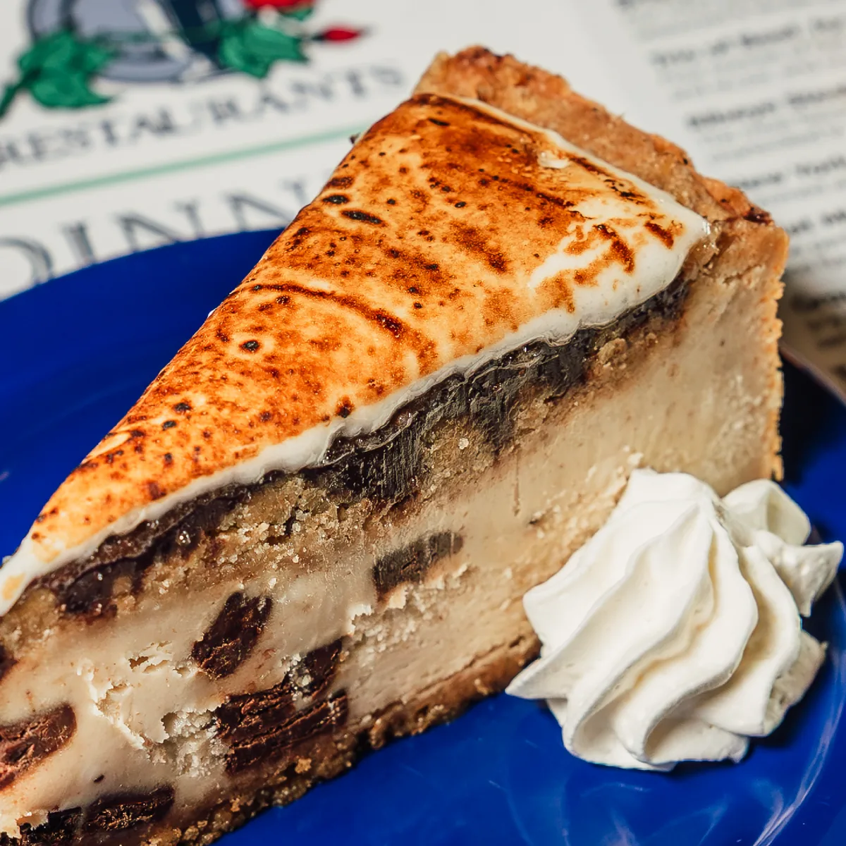 A slice of cheesecake with whipped cream on a blue plate