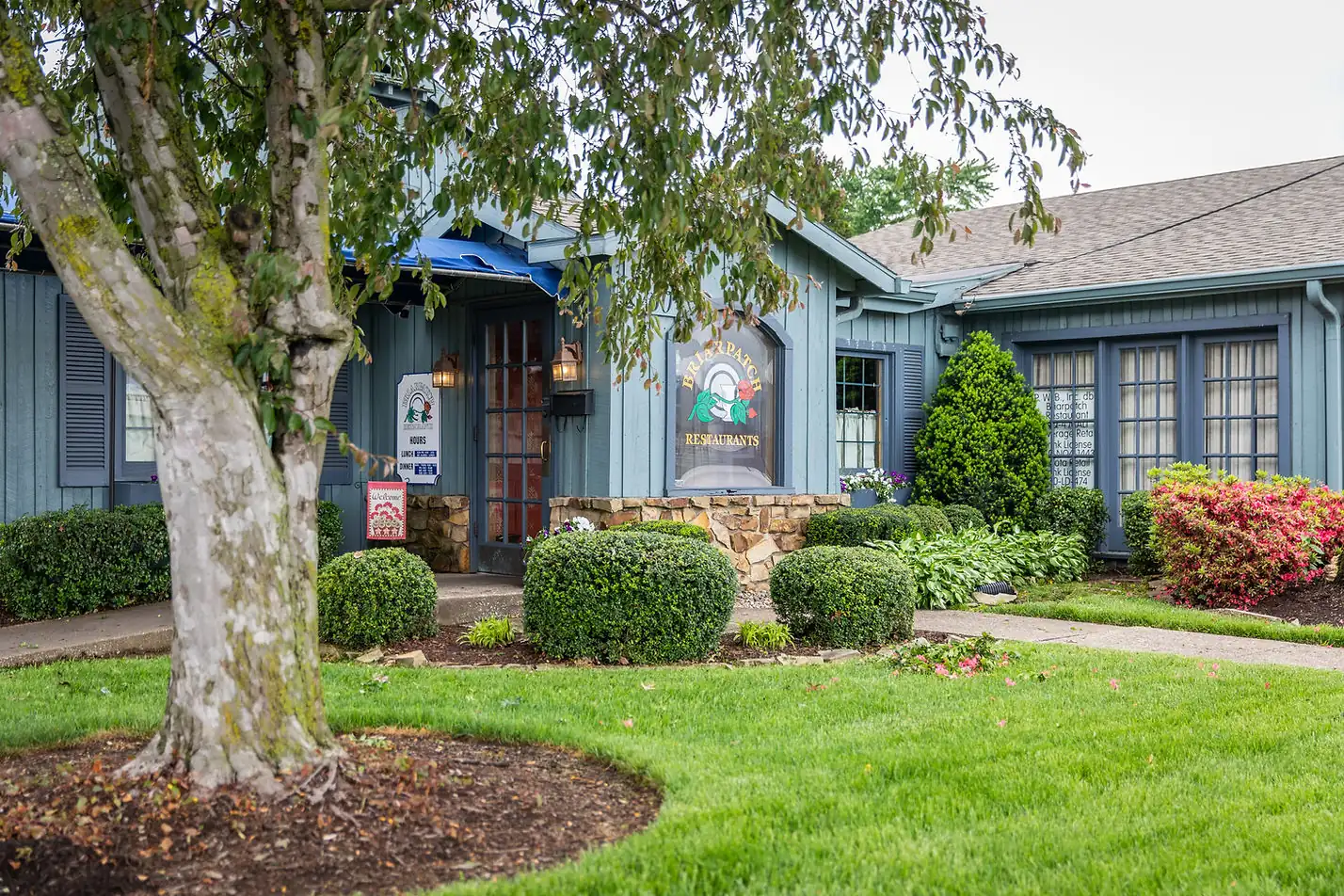 The Briarpatch restaurant building on Veach Road, with its garden and tree
